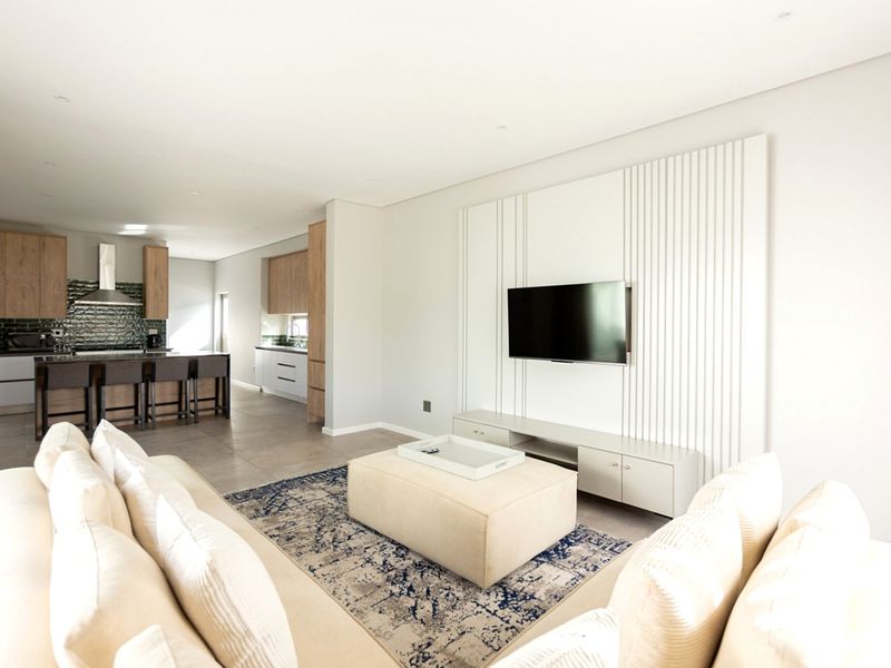Modern open-plan living area featuring a contemporary kitchen with island, sleek cabinetry, and a stylish feature wall with integrated television mount.