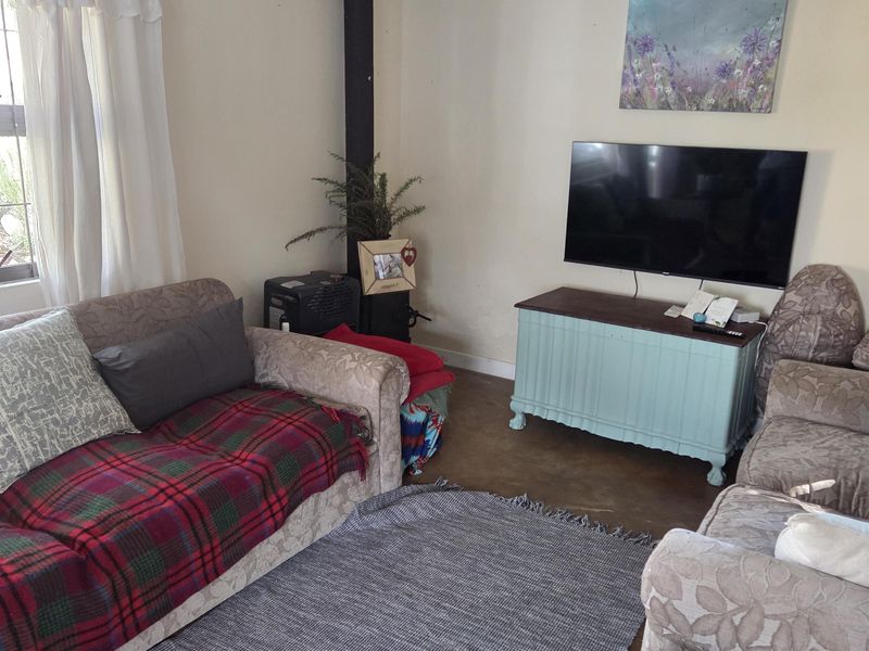 A cozy living room featuring a built-in wood-burning fireplace with a vertical flue pipe and durable concrete flooring.