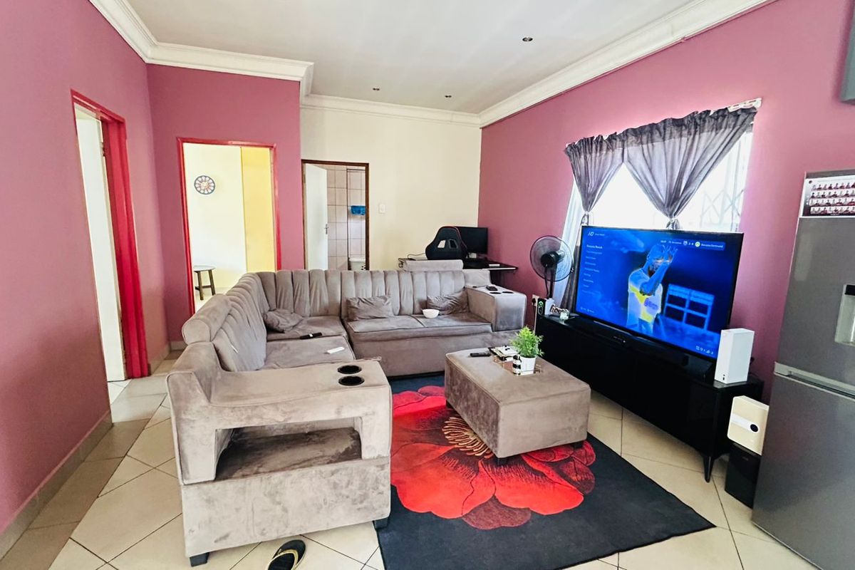 A living room featuring tiled flooring, recessed ceiling lights, and decorative cornicing, with access to adjacent rooms.