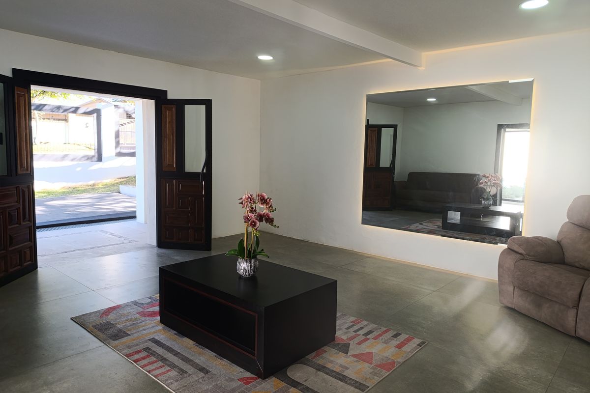 A bright and spacious living area featuring large double doors opening to the exterior, recessed ceiling lighting, and a prominent wall-mounted mirror.