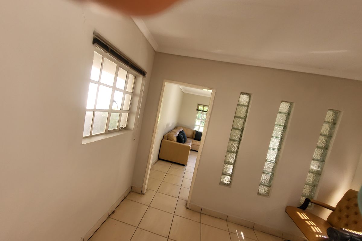 A living area featuring tiled flooring, a multi-pane window, and a decorative glass block feature wall, leading into an adjacent room.