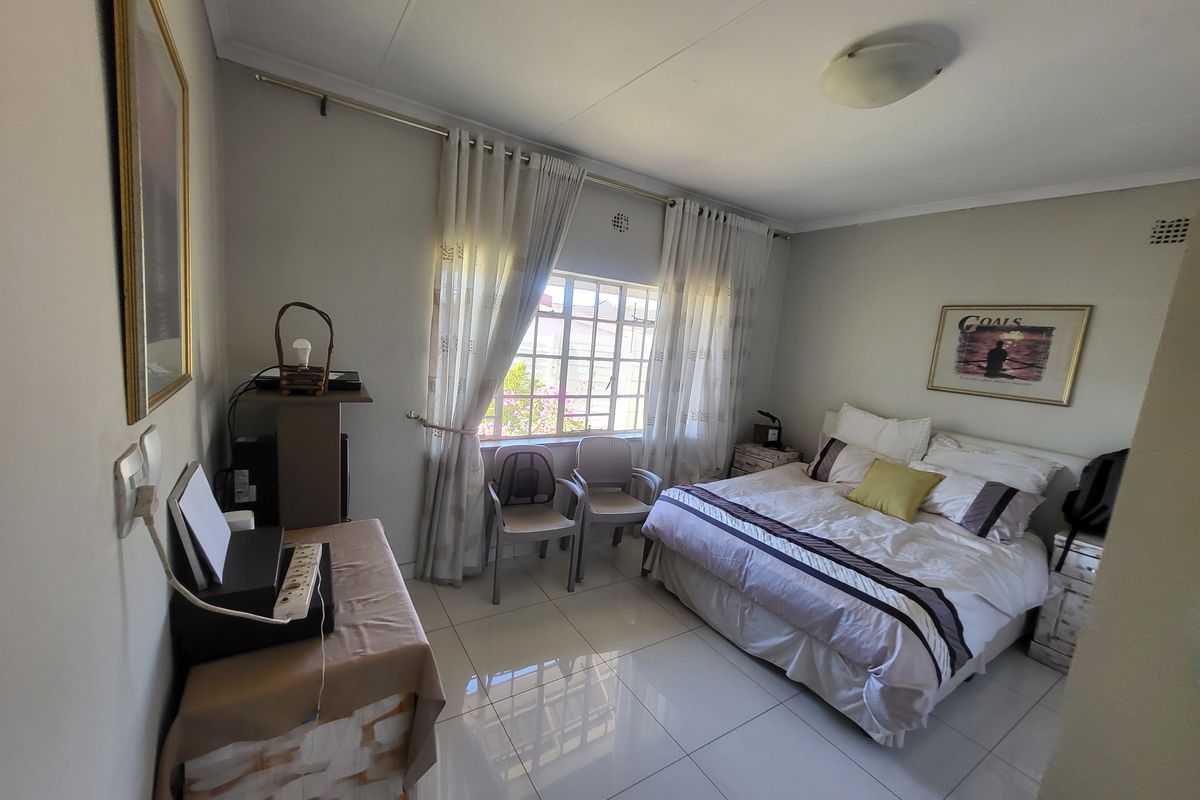 A well-lit bedroom featuring tiled flooring, a window with security bars, and neutral wall finishes, providing a comfortable and functional living space.
