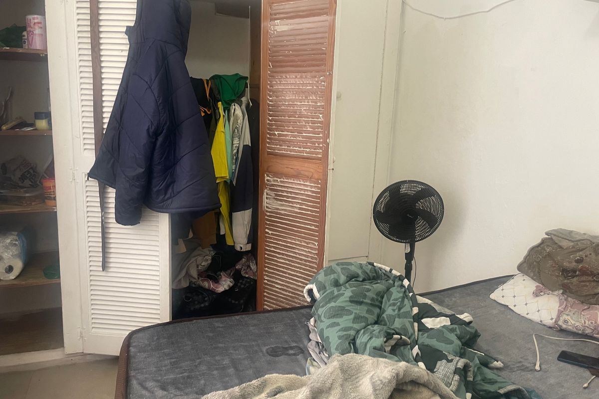 A bedroom featuring a built-in closet with louvered doors, showing signs of wear and requiring cosmetic updates.