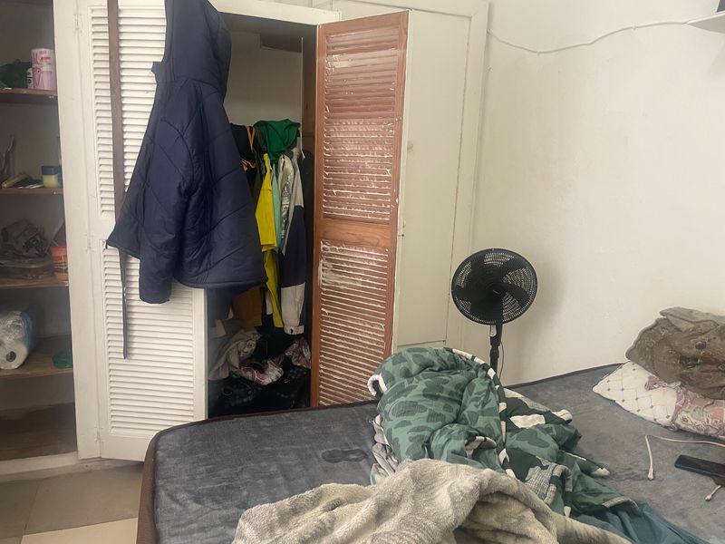 A bedroom featuring a built-in closet with louvered doors, showing signs of wear and requiring cosmetic updates.