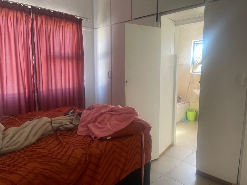 Bedroom featuring built-in cupboards and tiled flooring, with direct access to an en-suite bathroom.