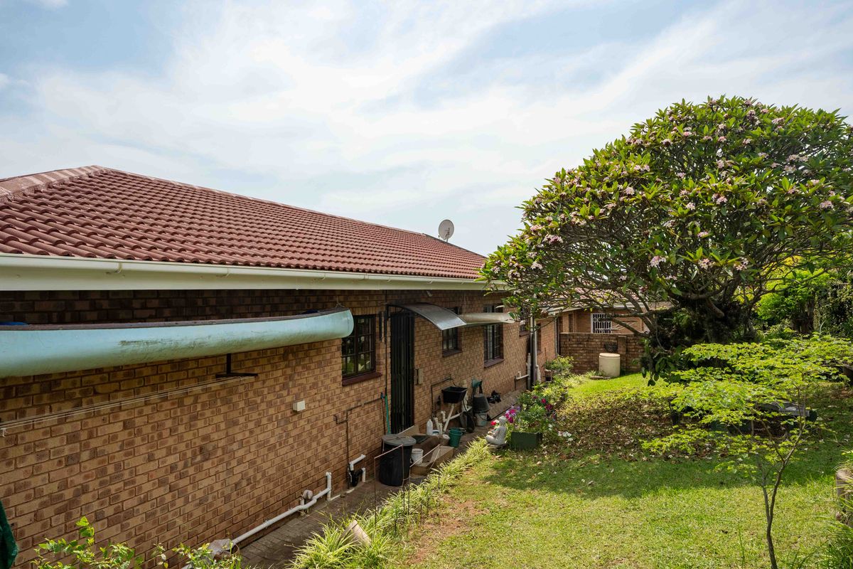 Rear exterior view of the townhouse featuring a brick facade, tiled roof, and established garden area.