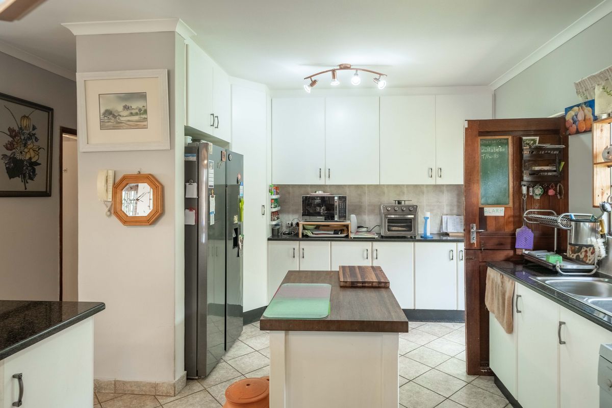 A functional kitchen featuring white cabinetry, granite countertops, a central island, and tiled flooring, offering a practical layout for daily meal preparation.
