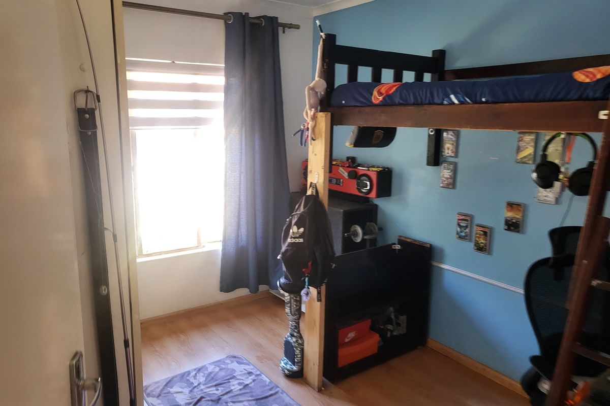 A bedroom featuring laminate flooring and a window with a curtain rod, currently utilized as a child's bedroom.