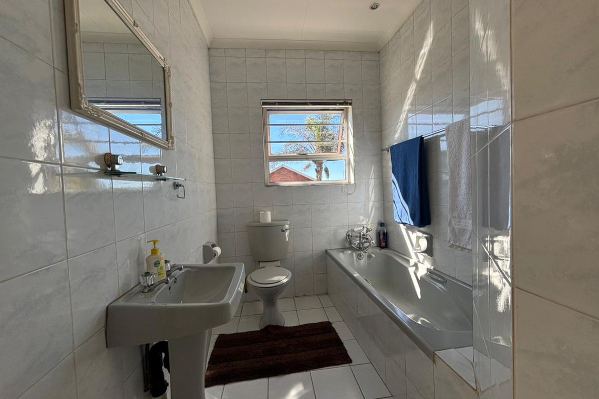 A functional bathroom featuring a pedestal basin, a standard bathtub, and full-height wall tiling.