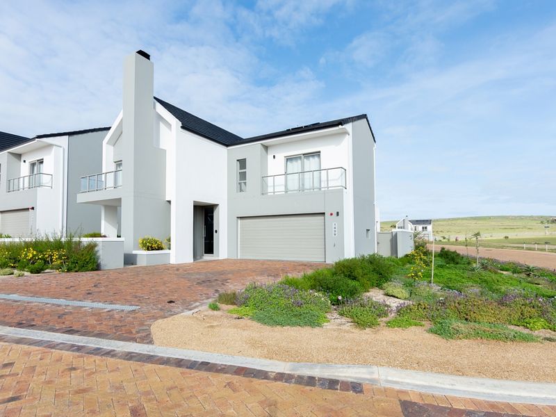 Modern double-story residential home featuring a brick-paved driveway, double garage, and an upper-level balcony with glass balustrades.