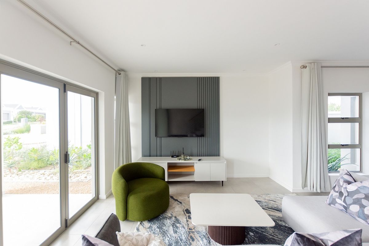 A bright and modern living room featuring a stylish grey feature wall, large sliding glass doors, and neutral tiled flooring.