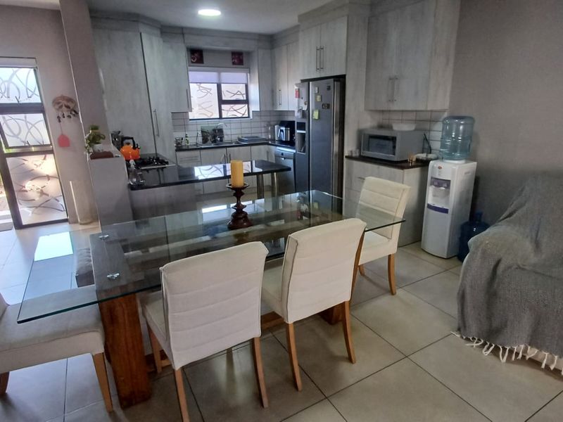 Open-plan kitchen and dining area featuring modern cabinetry, granite countertops, tiled flooring, and direct access to an outdoor patio through a sliding glass door.