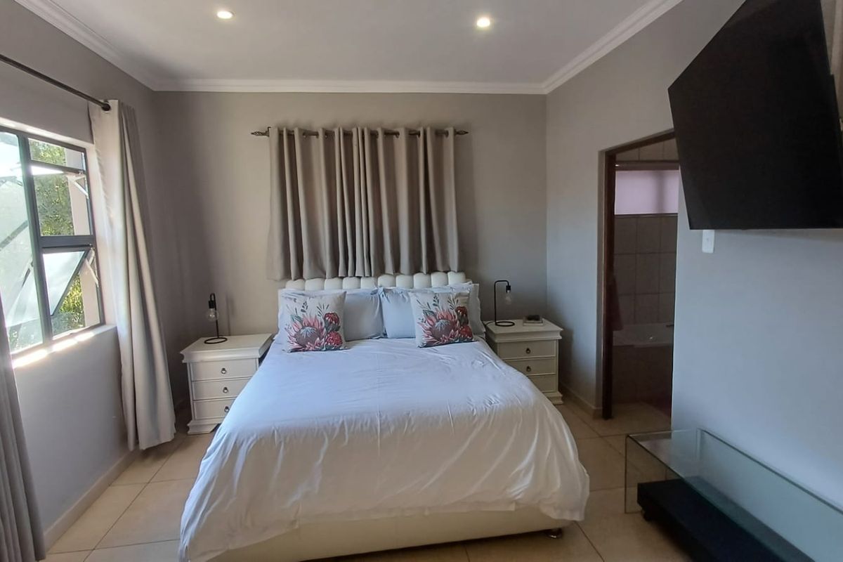 A well-maintained bedroom featuring tiled flooring, recessed downlighting, and an en-suite bathroom access point.