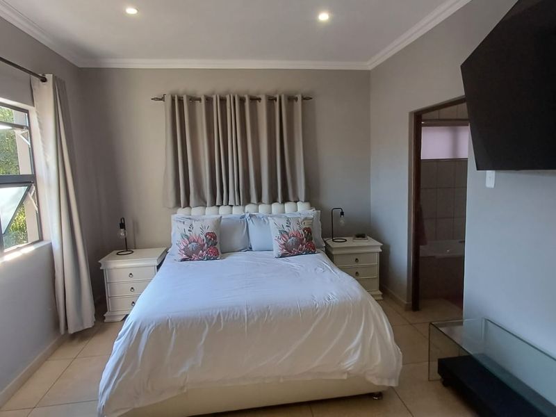 A well-maintained bedroom featuring tiled flooring, recessed downlighting, and an en-suite bathroom access point.