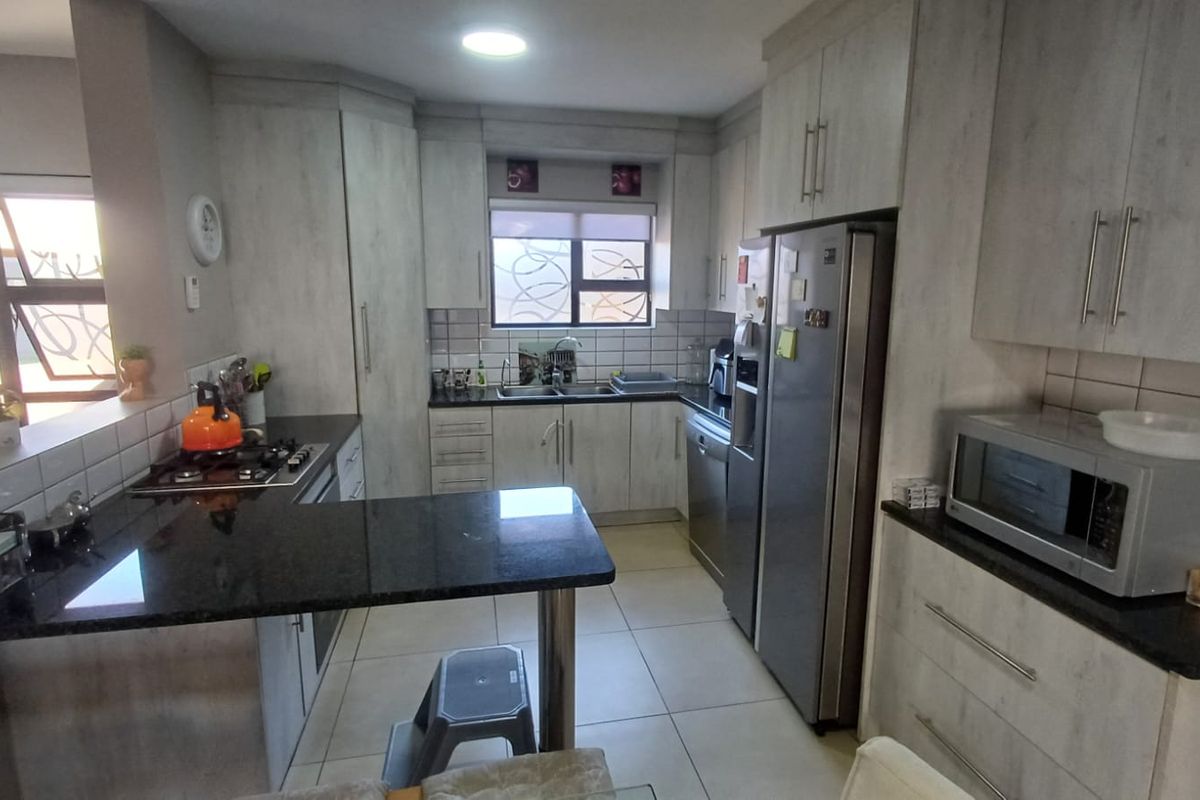 A functional kitchen featuring light-toned cabinetry, granite countertops, a gas hob, and tiled flooring, offering a practical layout for daily meal preparation.