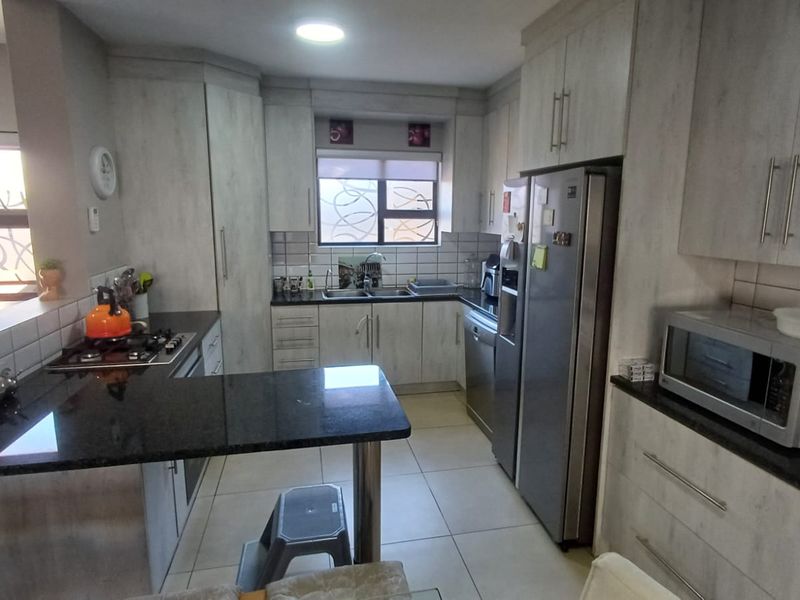 A functional kitchen featuring light-toned cabinetry, granite countertops, a gas hob, and tiled flooring, offering a practical layout for daily meal preparation.