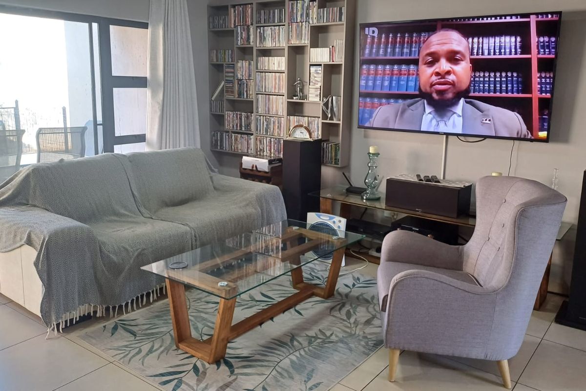 A comfortable living room featuring tiled flooring, a built-in shelving unit, and large sliding glass doors providing access to the outdoor area.