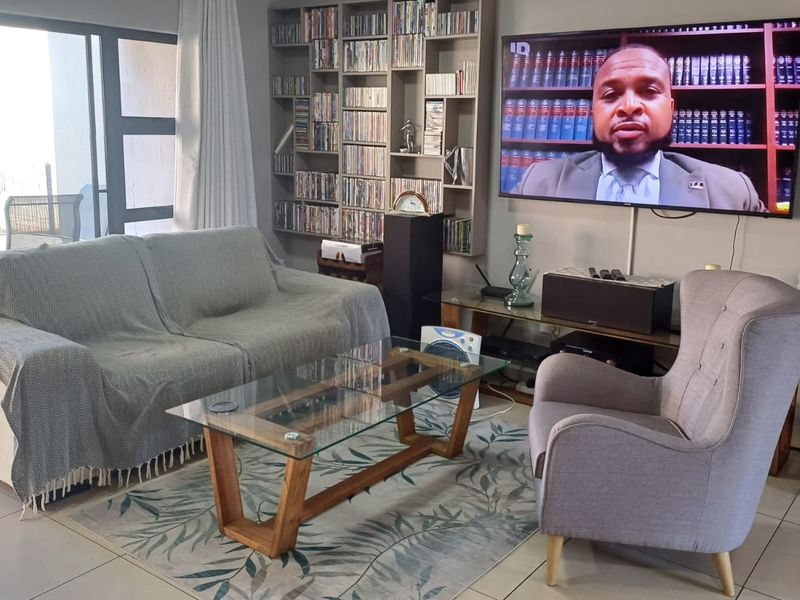 A comfortable living room featuring tiled flooring, a built-in shelving unit, and large sliding glass doors providing access to the outdoor area.