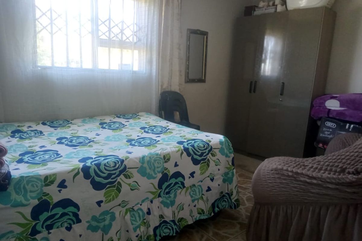 A functional bedroom featuring tiled flooring, a built-in wardrobe, and a window fitted with security bars.