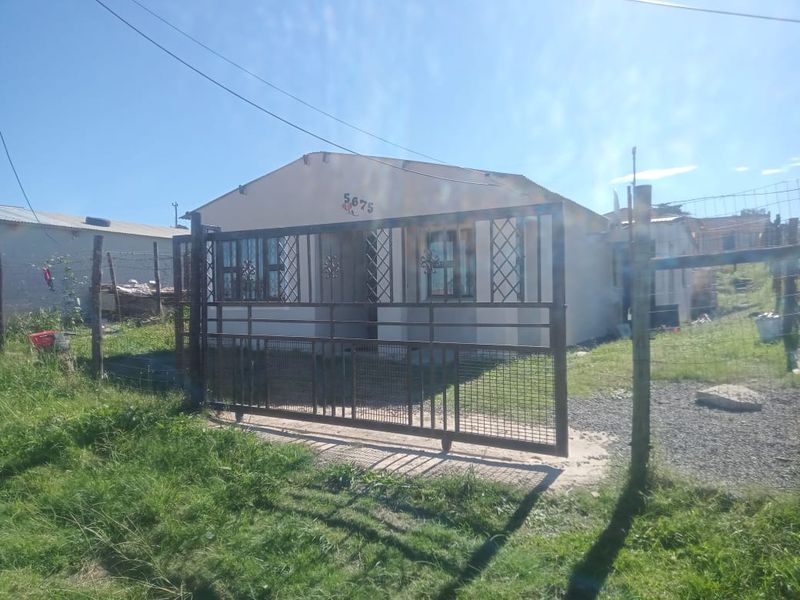 Front view of a single-story house featuring a metal security gate, window security bars, and a fenced yard area.