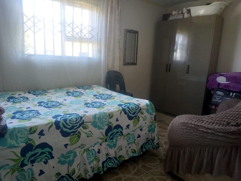 A functional bedroom featuring tiled flooring, a built-in wardrobe, and a window fitted with security bars.