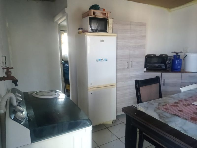 A functional kitchen area featuring tiled flooring and built-in cabinetry, requiring cosmetic updates to the walls and ceiling to improve the overall finish.