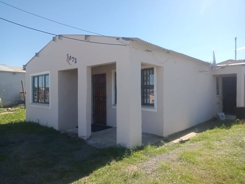 A single-story residential property featuring a plastered facade, corrugated metal roof, and security features including window bars and a front security gate.