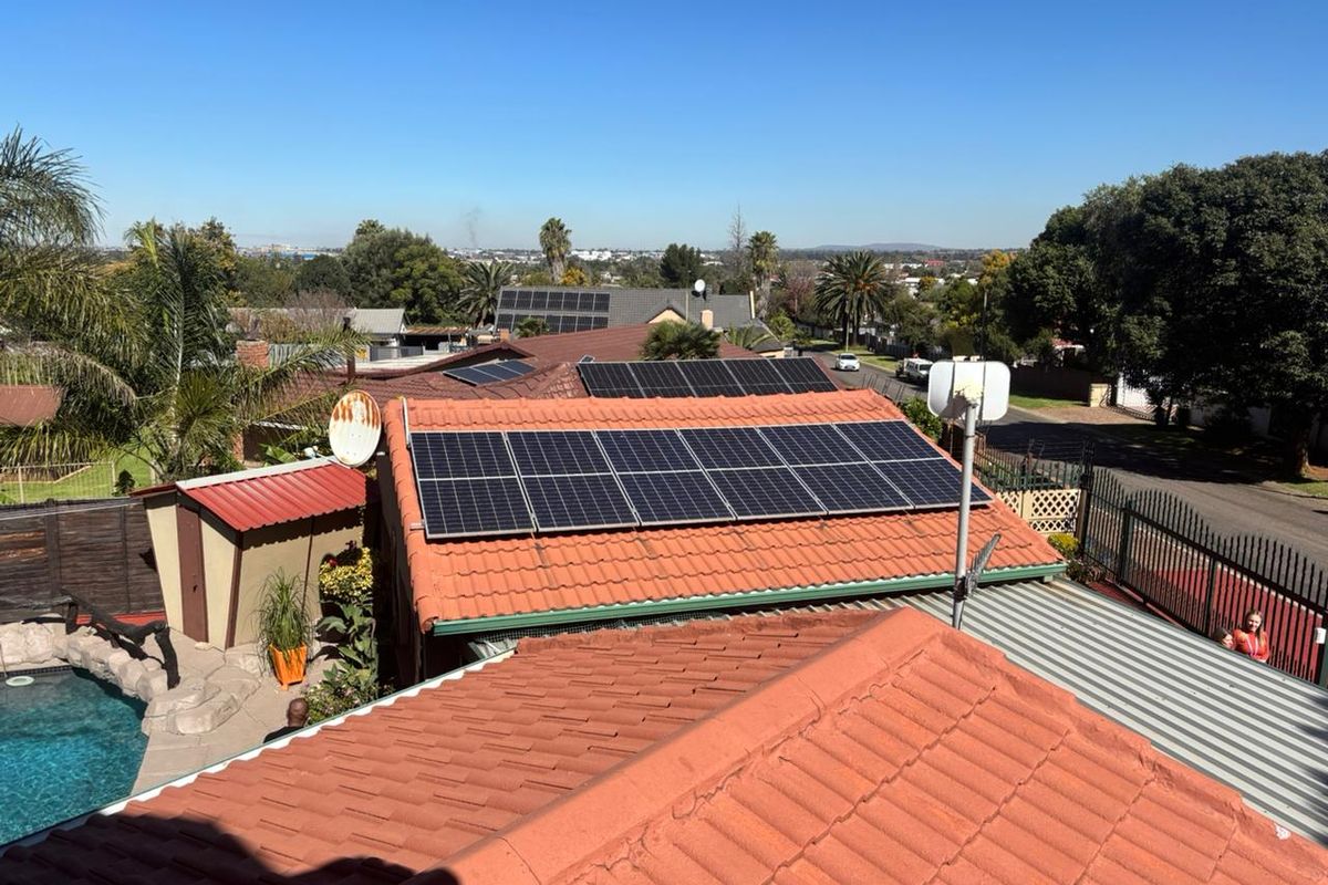 Elevated view of the property roof featuring installed solar panels, terracotta roof tiles, and a glimpse of the backyard pool area.