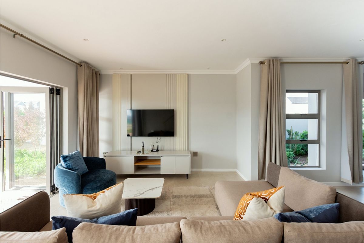 A bright and modern living room featuring decorative wall paneling, recessed lighting, and bi-fold doors that open to the garden.