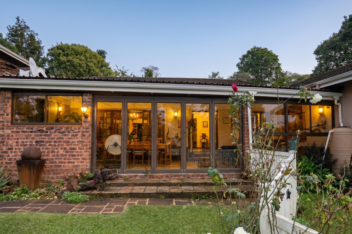Rear view of the house featuring a brick facade, large folding glass doors opening onto a tiled patio, and an integrated water tank.
