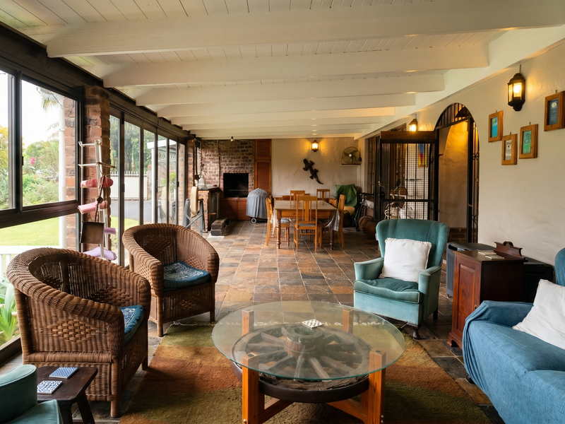 Spacious enclosed patio featuring slate tile flooring, exposed beam ceiling, and a built-in brick fireplace, offering a comfortable transition to the garden.