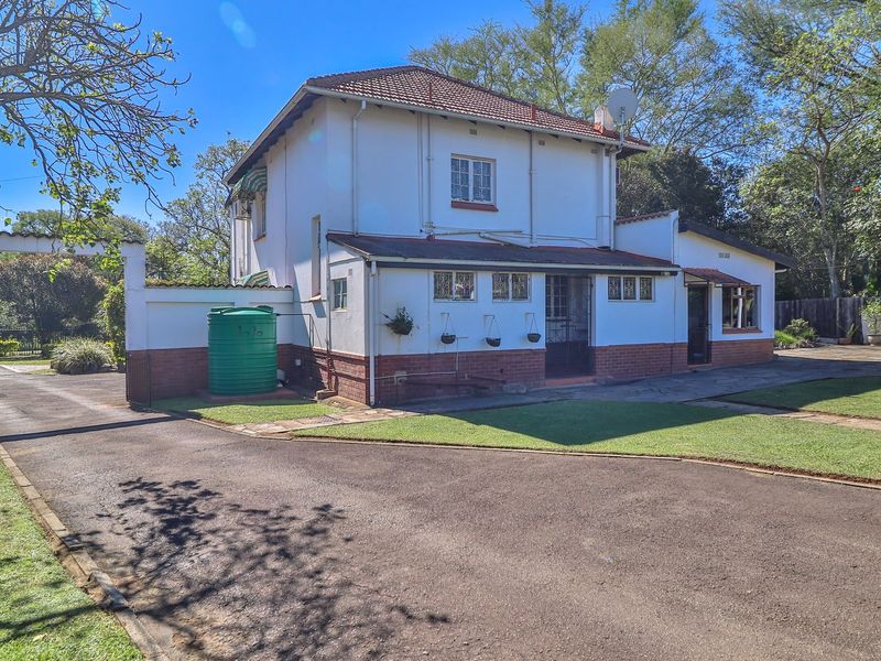A well-maintained two-story residential property featuring a paved driveway, brick base detailing, and an integrated water storage tank.
