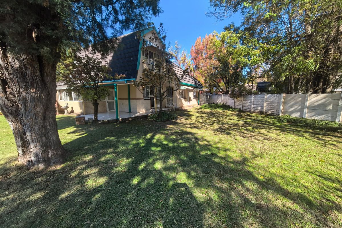 Rear view of the property featuring a spacious garden, covered patio area, and a balcony overlooking the backyard.