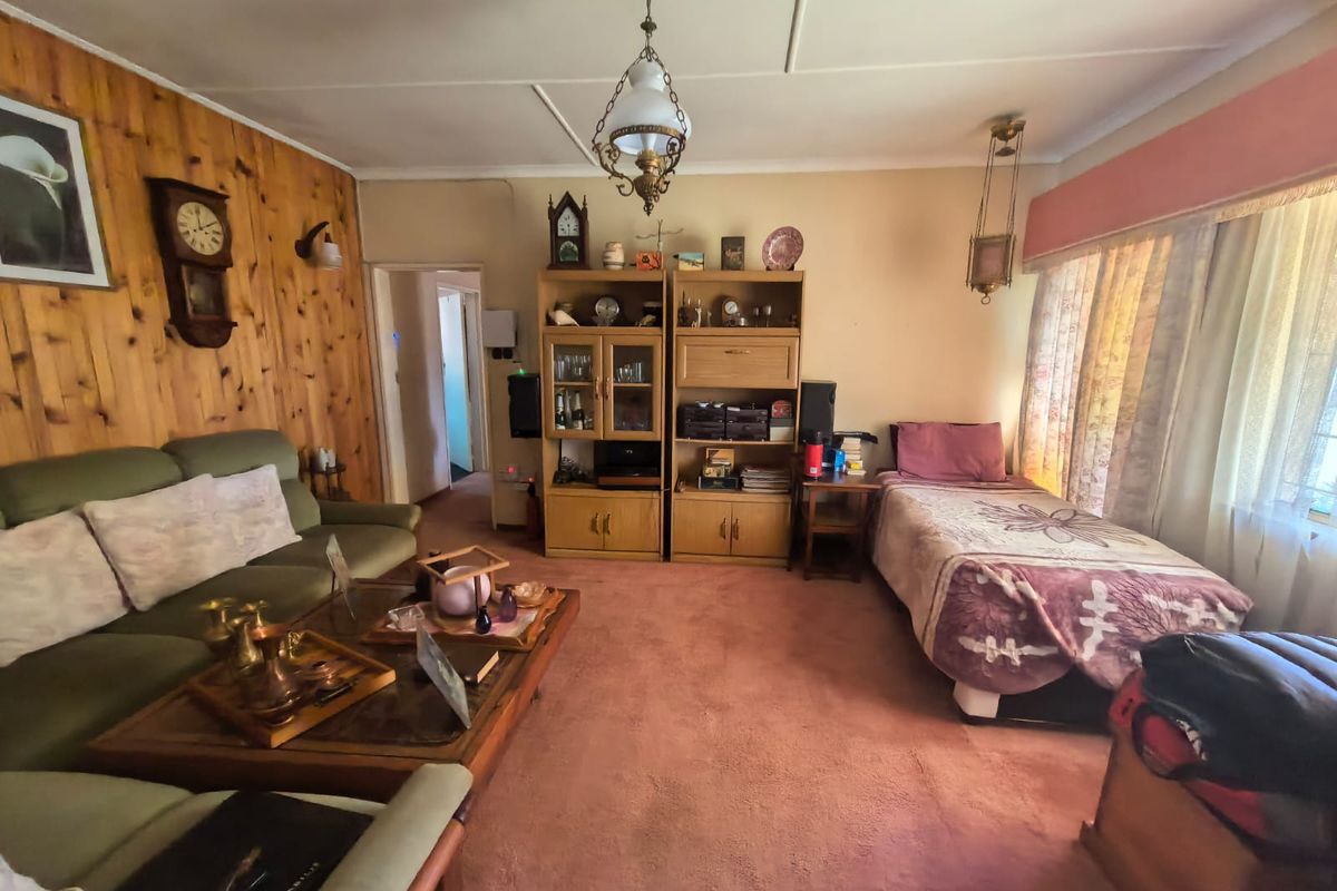 A dated living area featuring wood-paneled walls, carpet flooring, and a central ceiling light fixture, offering potential for modernization.