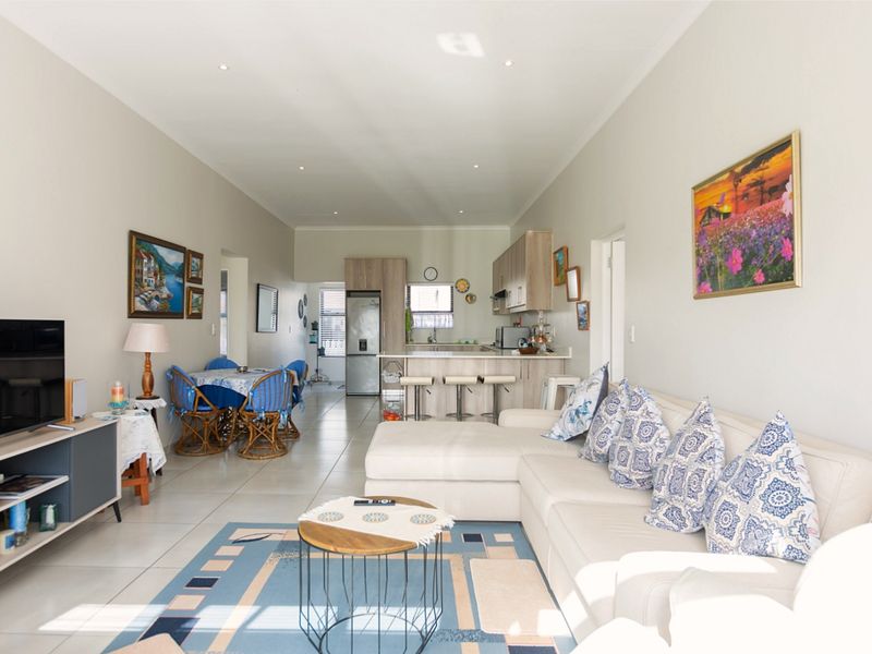 Spacious open-plan living area featuring a modern kitchen with island, tiled flooring, and recessed lighting, creating a bright and functional family space.