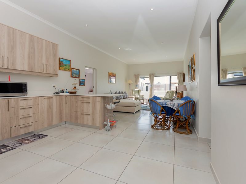 Spacious open-plan living area featuring a modern kitchen with light wood cabinetry, stone countertops, and seamless flow to the dining and lounge space.