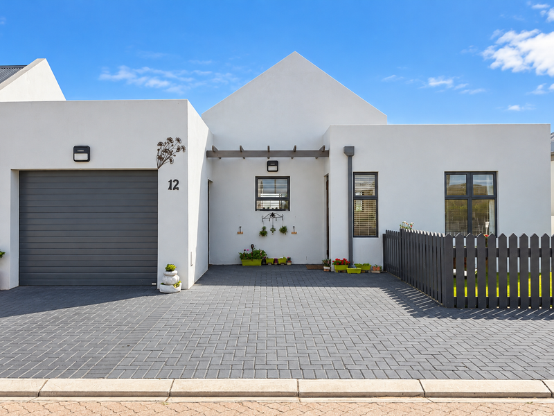 Modern single-story home featuring a clean white facade, paved driveway, single garage, and a charming timber pergola entrance.
