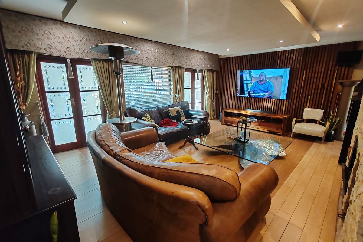 A well-appointed living room featuring timber slat wall paneling, recessed ceiling with downlights, and laminate flooring, providing a warm and modern atmosphere.