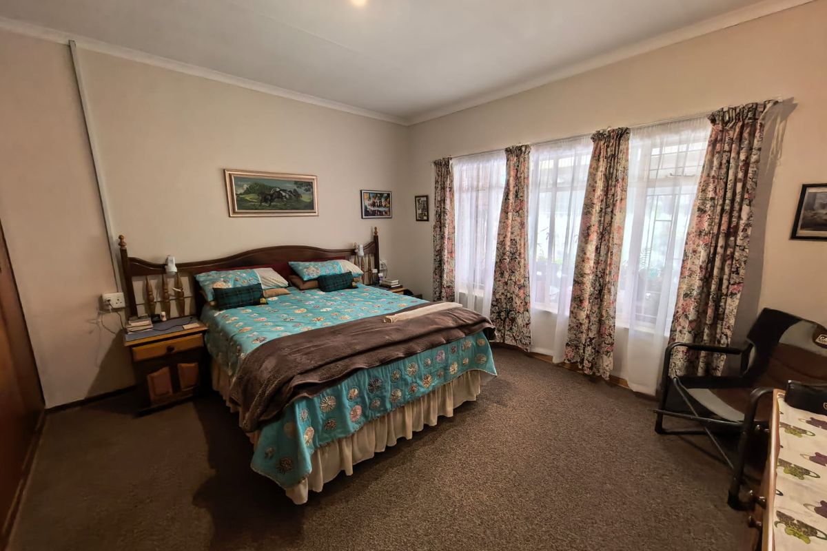 A spacious bedroom featuring carpeted flooring, built-in wardrobe storage, and large windows that allow for natural light.