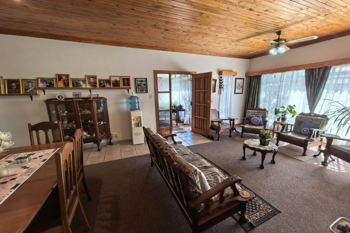 Spacious living area featuring a warm timber-clad ceiling, ceiling fan, and a mix of tiled and carpeted flooring with access to an adjoining room.