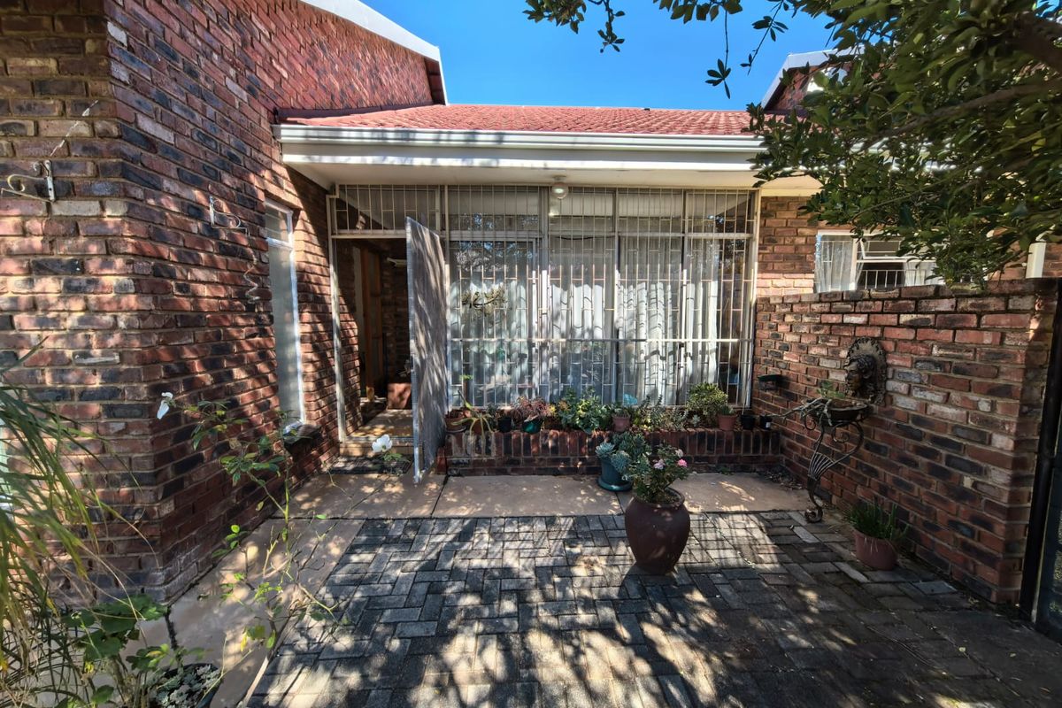 A private rear courtyard featuring face brick walls, a paved patio area, and secure access with metal security gates and window bars.