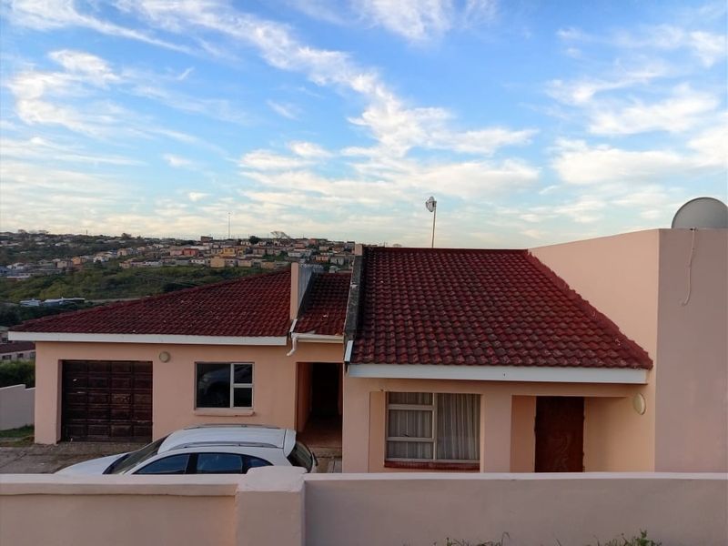 Front elevation of a single-story residential house featuring a tiled roof, integrated garage, and boundary wall with views of the surrounding neighborhood.