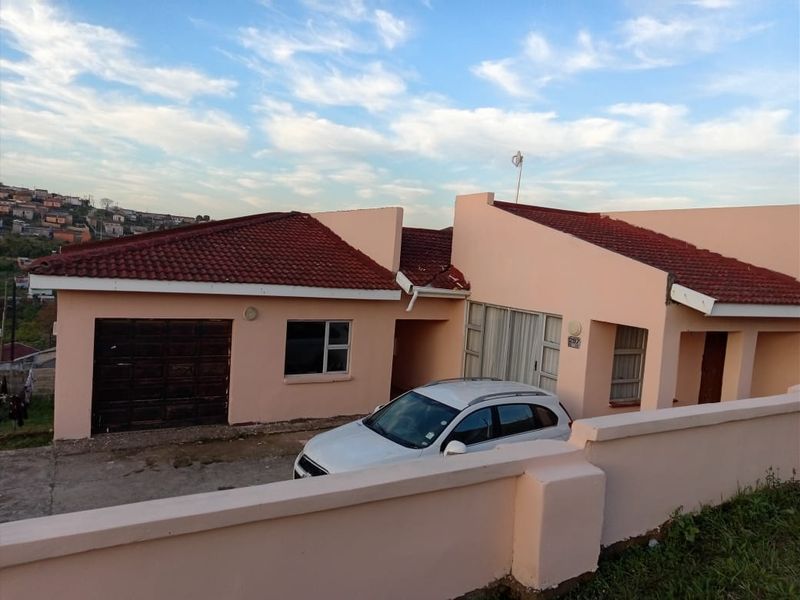 Front elevation of a single-story house featuring a tiled roof, attached garage, and a perimeter boundary wall.