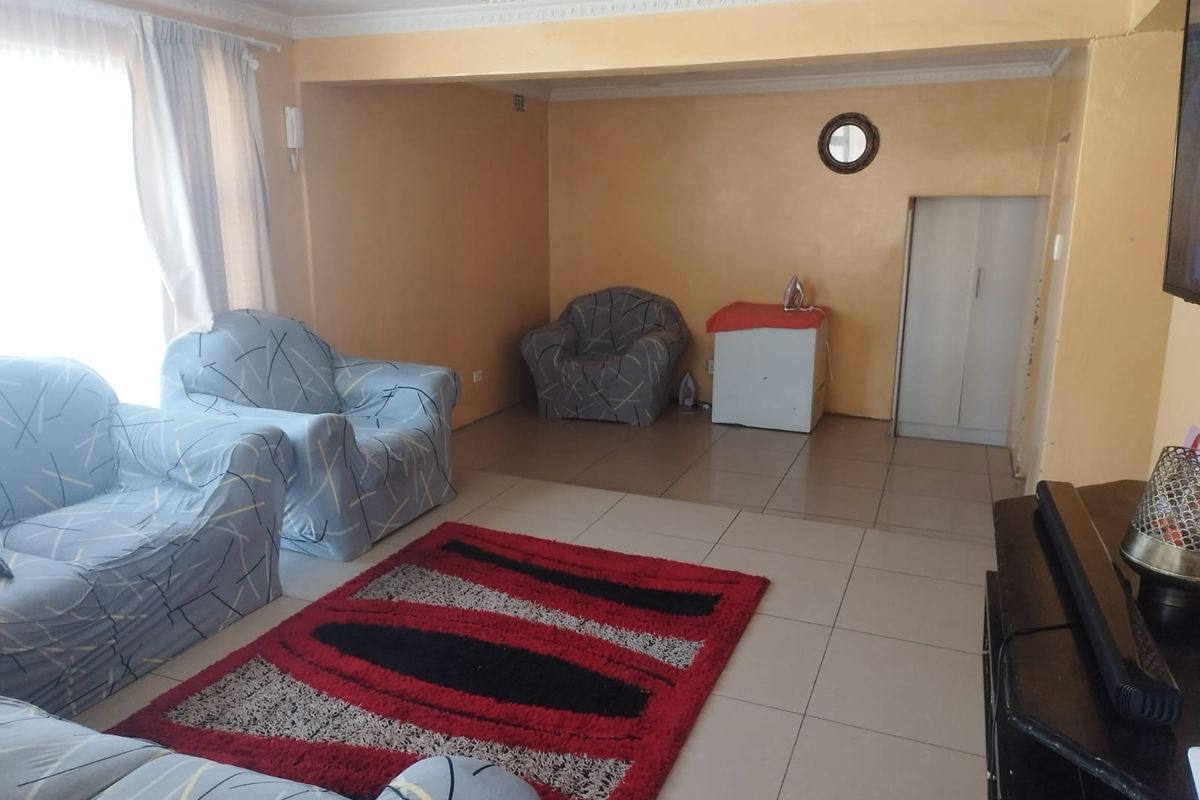 A spacious living room featuring tiled flooring, neutral wall tones, and decorative ceiling cornicing, providing a functional and open living area.