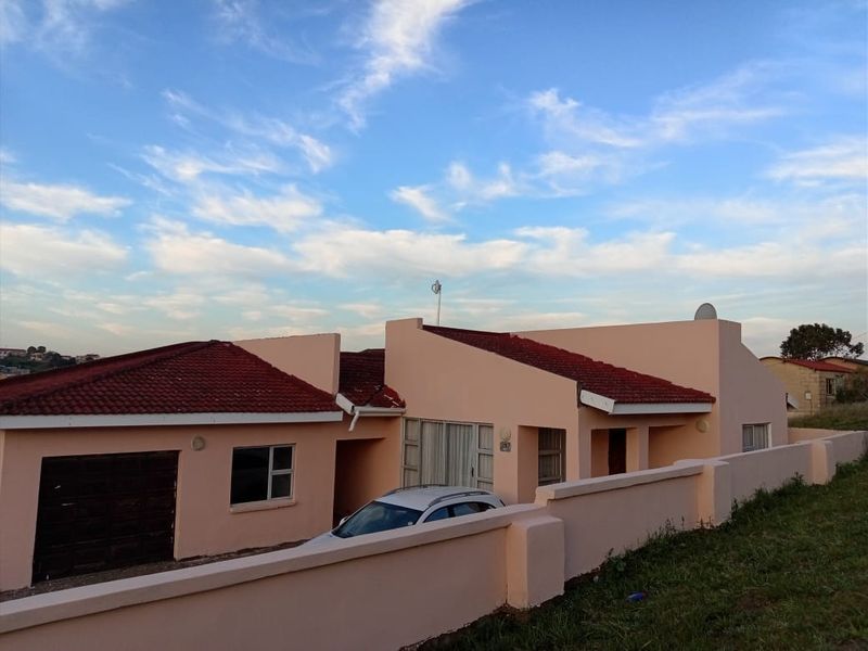Front exterior view of a single-story house featuring a tiled roof, attached garage, and perimeter boundary wall.