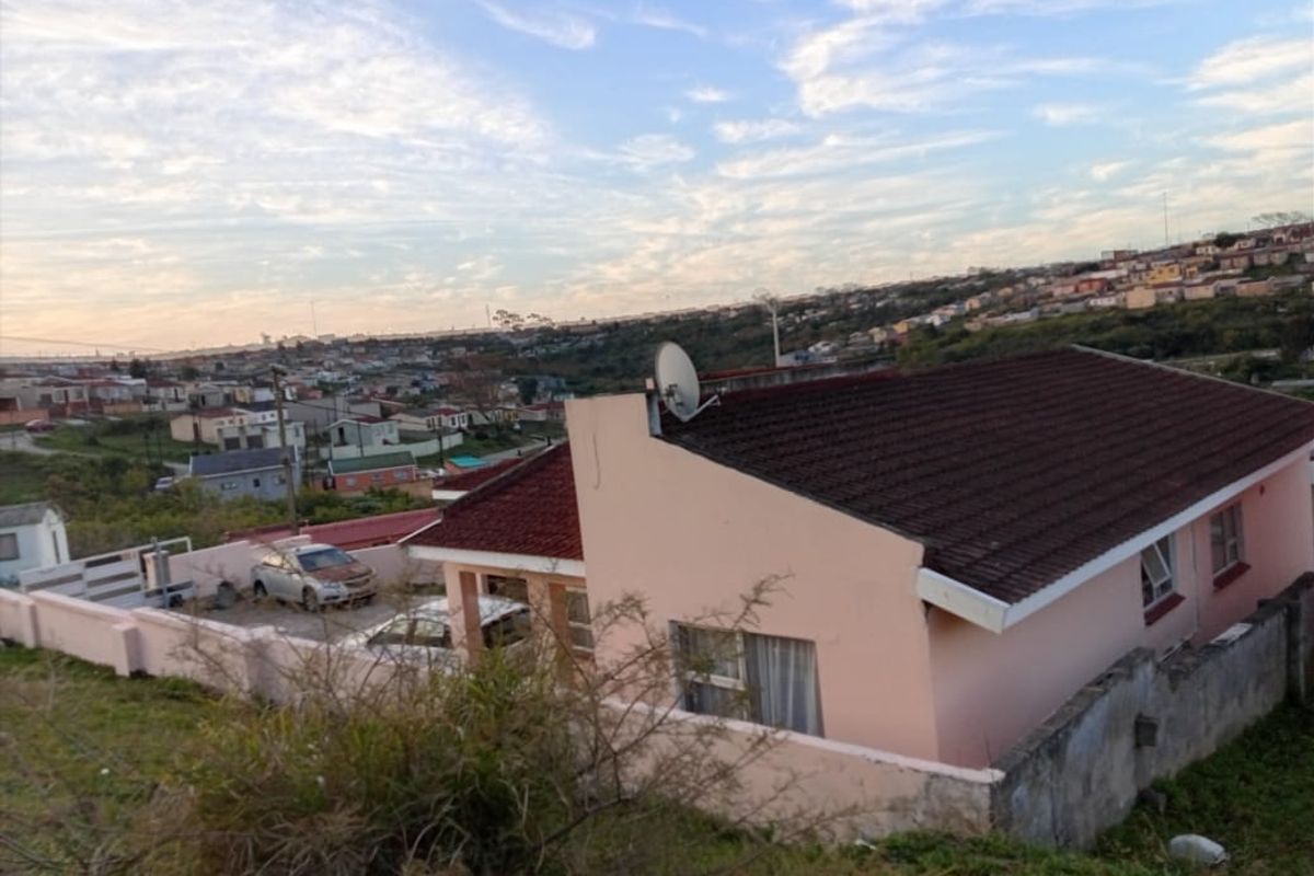 An elevated view of a residential property featuring a tiled roof, boundary walls, and a satellite dish, set within a suburban neighborhood.