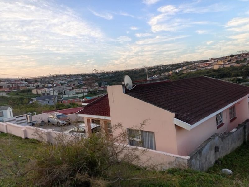 An elevated view of a residential property featuring a tiled roof, boundary walls, and a satellite dish, set within a suburban neighborhood.