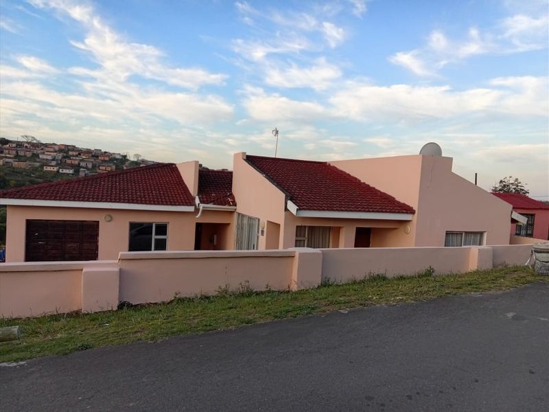 Front exterior view of a single-story residential house featuring a tiled roof, boundary wall, and integrated garage.