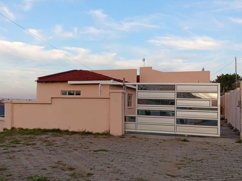 Front exterior view of the property featuring a sliding gate, perimeter wall, and paved driveway area.