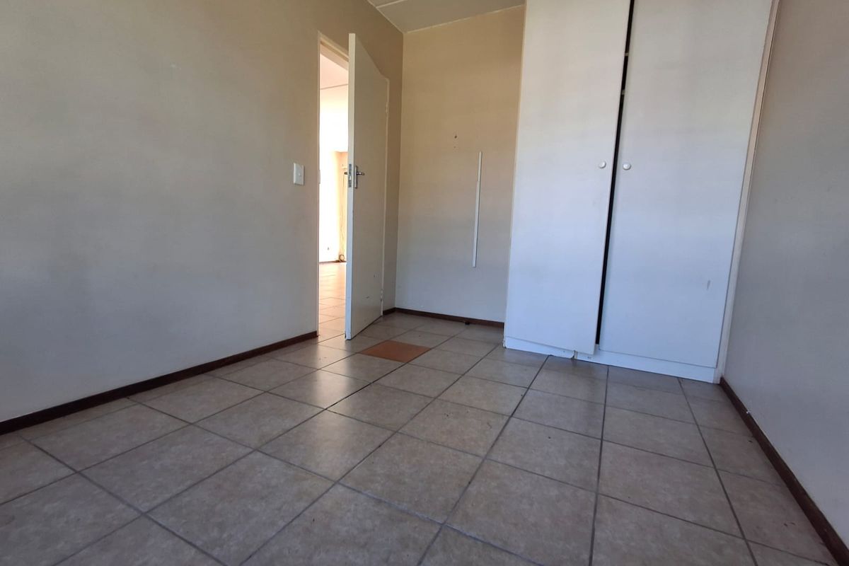 An empty bedroom featuring tiled flooring and built-in cupboards, requiring minor cosmetic updates to restore its appeal.